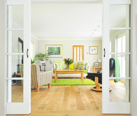 View into a room througn windowed garden doors. The furniture is white, light wood and brignt green.